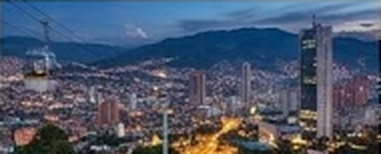 Medellín iluminada al atardecer en el Valle de Aburrá, con el cable aéreo